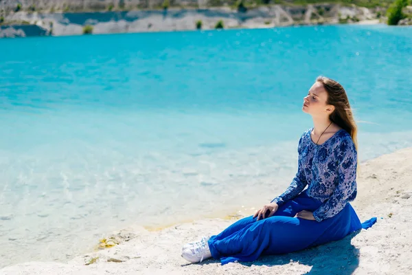 Genç sevimli kız göl kıyısında oturur