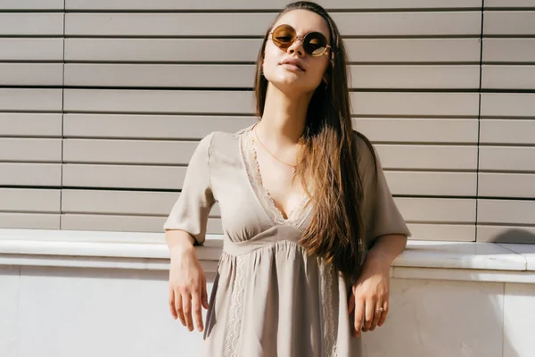 Una bella ragazza con i capelli lunghi appoggiata al muro della casa — Foto Stock