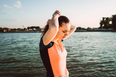 Bir spor kız saçını bir nehir arka planı bağları