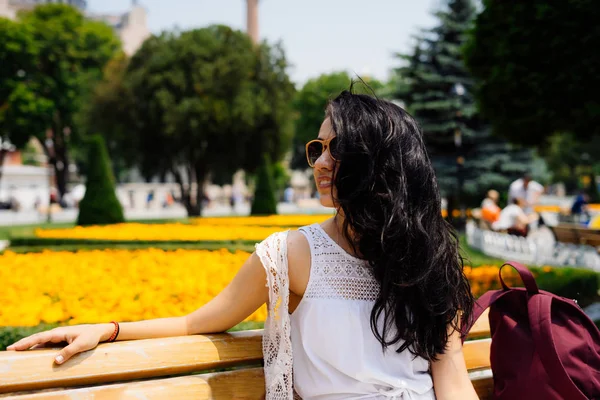 Young dark-haired girl sitting on a bench in the park — Stock Photo, Image