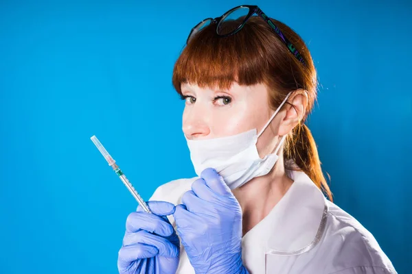 Mujer doctora con una máscara sostiene una jeringa en su mano — Foto de Stock