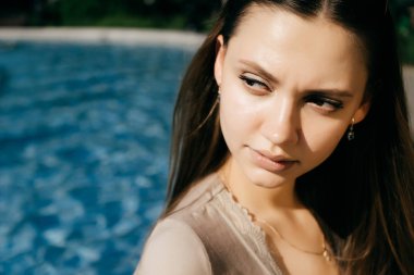Genç esmer kız havuz kenarında duruyor