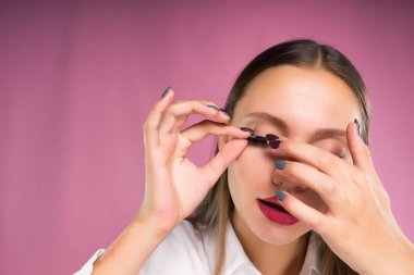 Genç bir kadın sahte kirpik Yapıştırıcılar, kirpik uzatma türünü seçer. Yüz bakımı, güzellik.