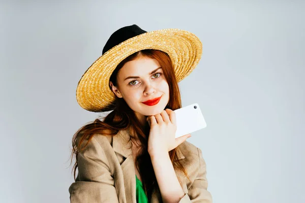 Bella giovane donna in un cappello sta tenendo uno smartphone in mano. Adolescente con cellulare . — Foto Stock