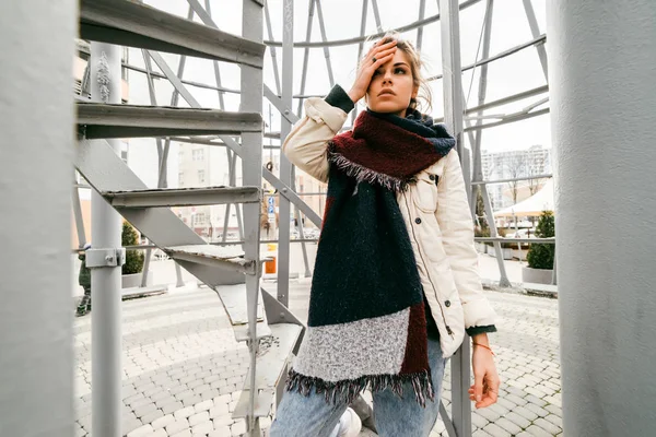 Una giovane donna stanca per strada tiene la testa e aspetta qualcuno — Foto Stock