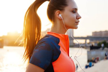 Genç atletik kadın atlet parkında çalışır ve müzik dinliyor