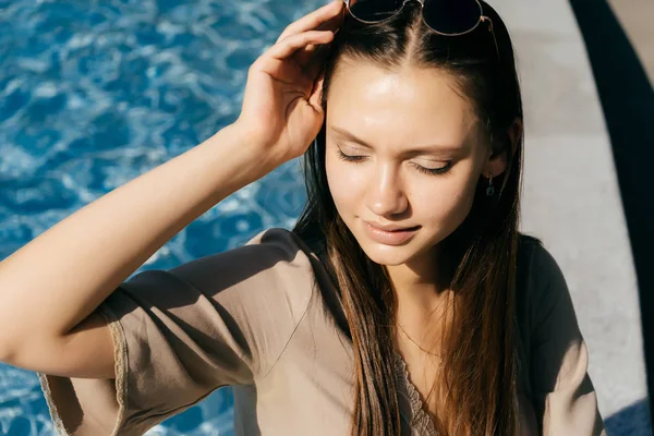 Αίγλη κορίτσι που κάθεται δίπλα στην πισίνα σε μια καυτή ηλιόλουστη ημέρα — Φωτογραφία Αρχείου