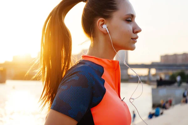 Genç atletik kadın atlet parkında çalışır ve müzik dinliyor