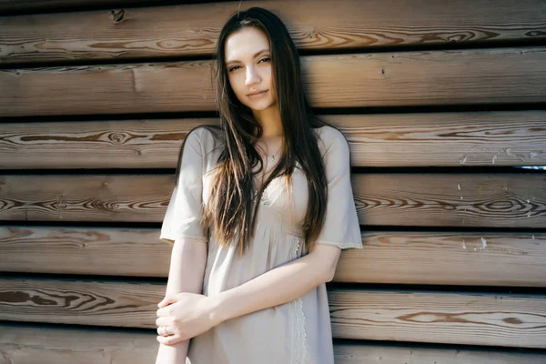 Ritratto di una bella ragazza in abito beige su sfondo di legno — Foto Stock