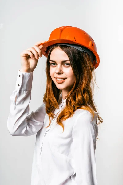 Uma menina em um capacete de construção olha para a câmera e sorri — Fotografia de Stock