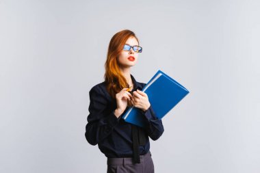 Ciddi kadın memur gözlüklü kameraya benziyor. Klasörlerde elleri ile bir öğrenci