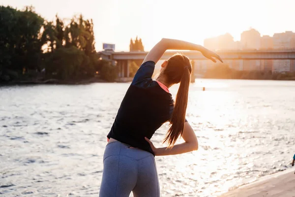 Kvinnan gör yoga, stretching på Älvstranden i staden — Stockfoto