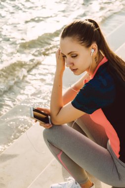 Bir kadın kaçak telefon elinde tutan ve bir egzersiz yaptıktan sonra dinlenme