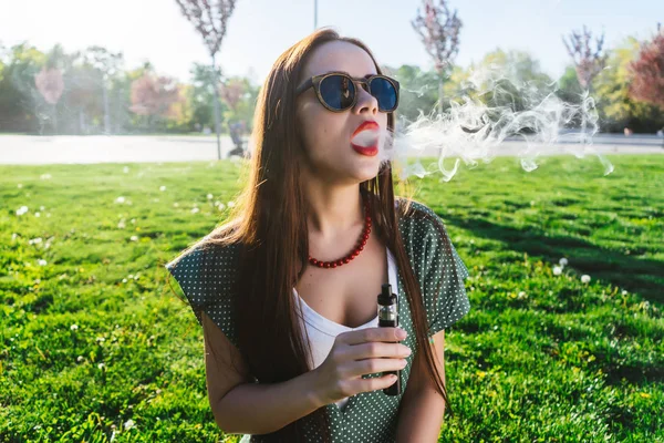 Feliz moda sonriente Mujer en gafas de sol fumar vapor en la calle, humo — Foto de Stock