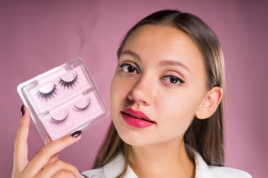Genç kadın sahte kirpik elinde tutar.