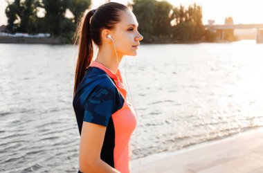 Bir kadın runner müziği dinliyor ve spor günbatımında çalış