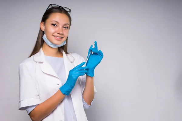 Bir şırınga elinde tutan ve gülümseyen genç kadın doktor — Stok fotoğraf