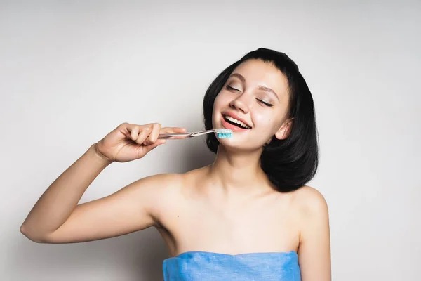 Menina em uma toalha escovando os dentes — Fotografia de Stock