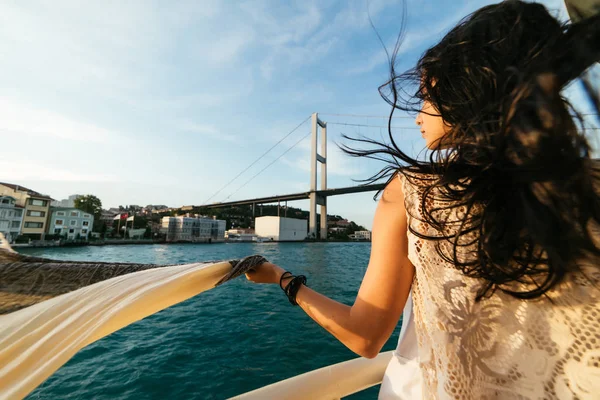 Giovane bella ragazza in una passeggiata attraverso Istanbul su una barca, ponte su uno sfondo — Foto Stock