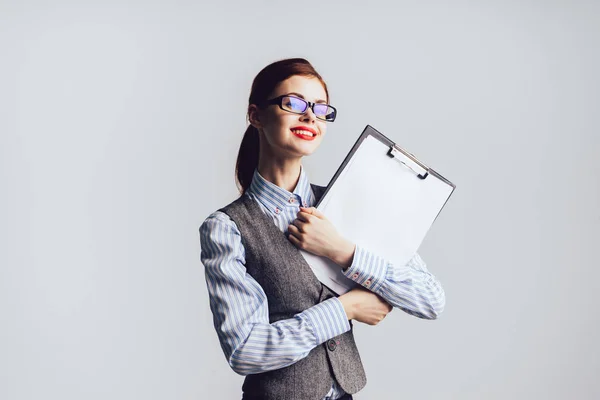 Eine hübsche junge Geschäftsfrau mit Brille und einem Anzug mit Papier in der Hand, die selbstbewusst lächelt — Stockfoto