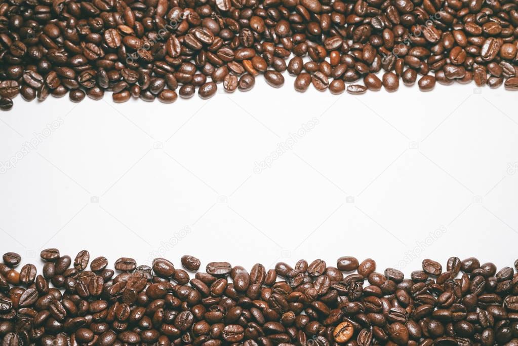 Frame of roasted coffee beans on white background