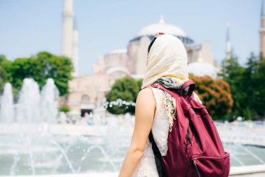 Bir eşarp ile cami ve Çeşme bir arka plan üzerine bir sırt çantası içinde tanınmayan bir kadın. Yaz tatili, gezgin