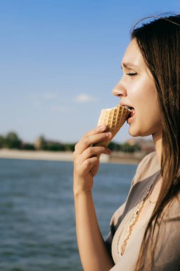 Genç kız nehir arka plan üzerinde dondurma yiyor, don't like