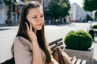 Dışarıda telefonla konuşan genç bir kadın.