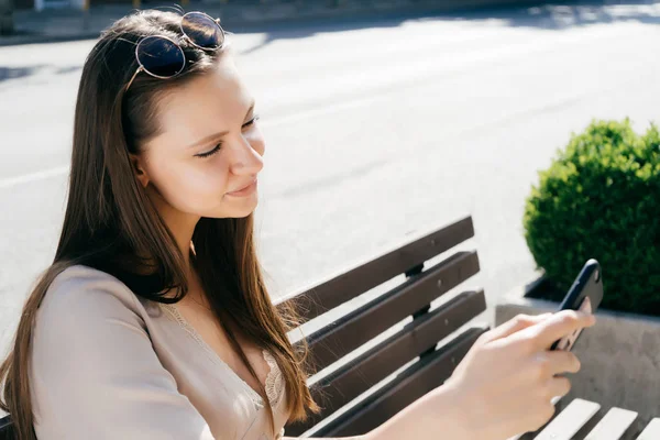 Young woman looks at smartphone, uses application, media — Stock Photo, Image