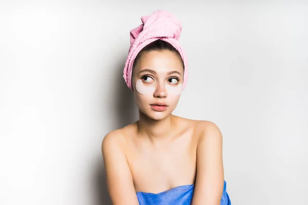 Uma menina com uma máscara de gel sob os olhos olha para a esquerda — Fotografia de Stock