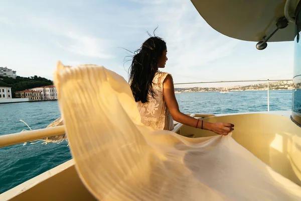 Девушка смотрит на город с лодки, закат на лодке — стоковое фото