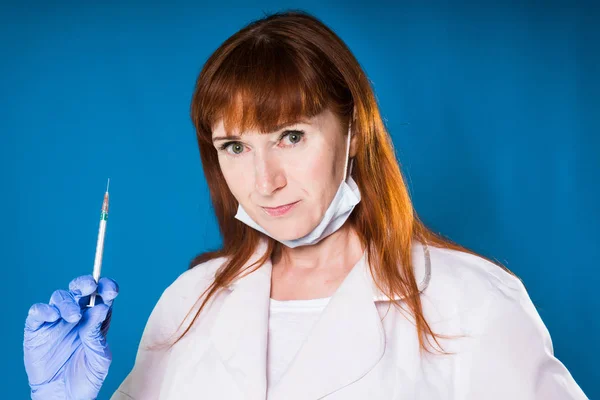 Dai capelli rossi ragazza in uniforme medica con una pugnalata nelle mani guardando intensamente nella fotocamera — Foto Stock