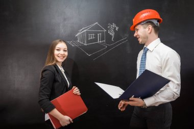 iş kadını ve adam kendi iş herkese göstermek ve gülümse. Adam onun kask koymak ve belgeler ile bir klasör tutar