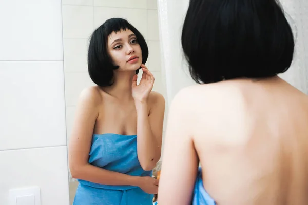Мила дівчина з коротким чорним волоссям після душу дивиться у дзеркало — стокове фото