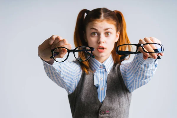 Engraçada menina ruiva com duas caudas segura em suas mãos dois pares de óculos — Fotografia de Stock