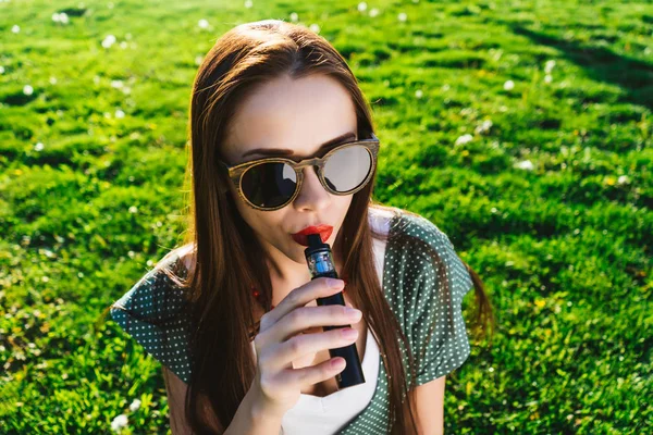 Mutlu moda gülümseyen kadın güneş gözlüğü vape Street, duman Sigara