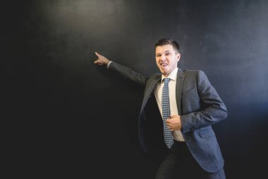 Bir erkek öğretmen siyah yazı tahtası için puan yazıyor, komik surat, kızgın