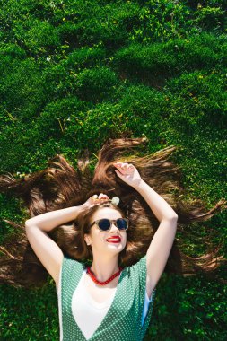 Sokakta, komik moda tarzı dinlendirici kız çim üzerinde yalan