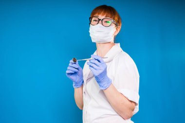 Bir sabahlık ve maske bir kadın doktor araçları onun elinde tutuyor