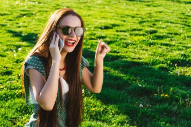 Mutlu kadın çim üzerinde bir şey gösteren gözlük kullanan mobil
