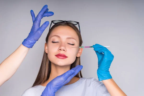 As mãos de um médico fazem injeções na cara de uma jovem — Fotografia de Stock