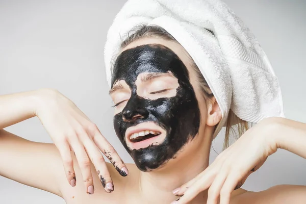 Sorrindo mulher alegre recebe máscara preta no rosto. Cuidados com a pele, poros limpos, esfoliação — Fotografia de Stock