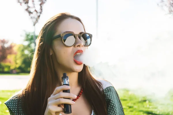 Счастливая мода улыбается Женщина в солнцезащитных очках, курящая на улице, дым — стоковое фото
