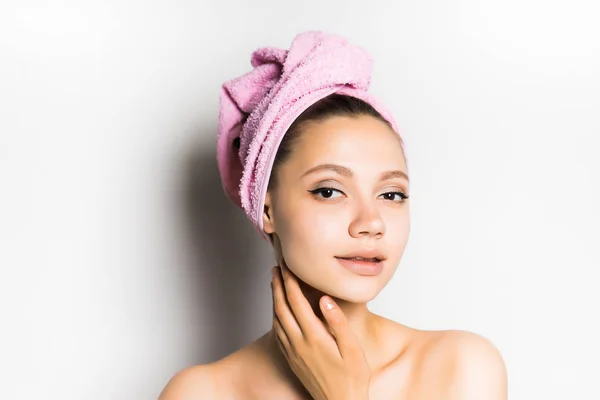 Linda chica con una toalla rosa en la cabeza mirando a la cámara, aislado — Foto de Stock