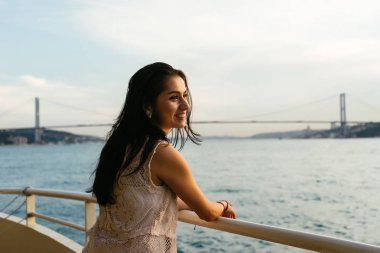 Günbatımı, cmiling denize bakarak mutlu bir genç kadın. Arka plan köprüde