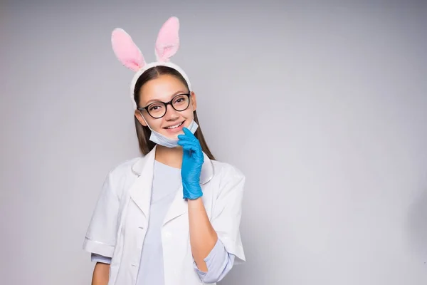 Sorridente infermiera ragazza in rosa lepre orecchie su sfondo bianco — Foto Stock