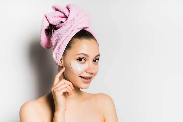 Sorrindo menina com uma toalha na cabeça coloca sobre a fundação rosto — Fotografia de Stock