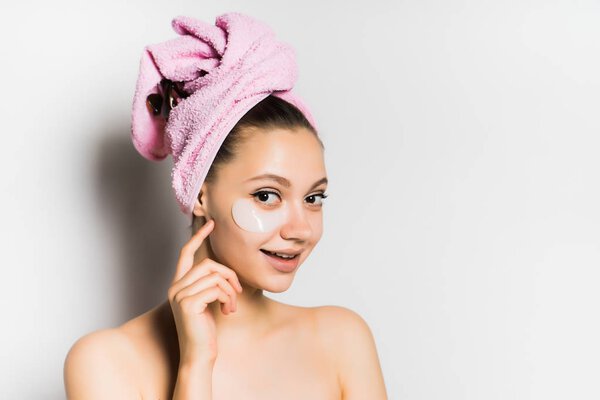 smiling girl with a towel on her head puts on the face foundation