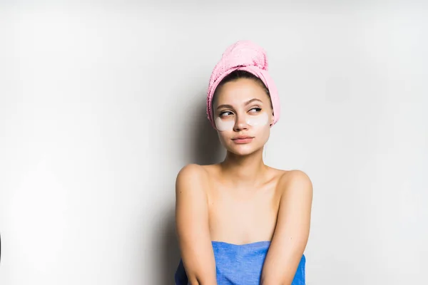 Menina pensativa com uma toalha amarrada em torno de sua cabeça com uma máscara em seu rosto — Fotografia de Stock