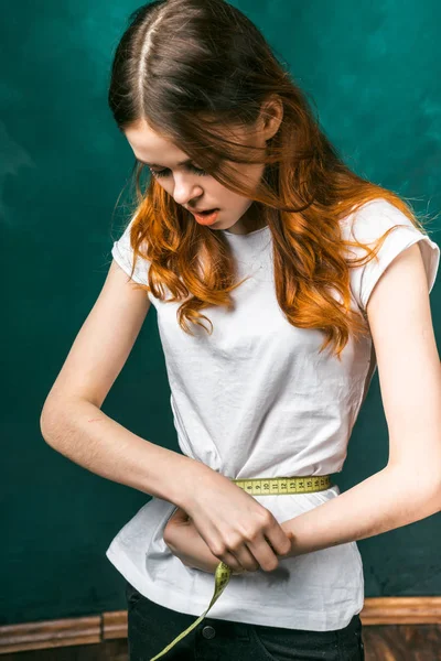 Menina surpreso em uma camiseta branca olha para o tamanho de sua cintura — Fotografia de Stock